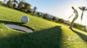A golf ball sitting on the edge of a hole.