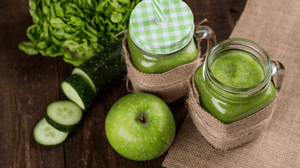 Jars of green juice with cucumber, apple, and herbs