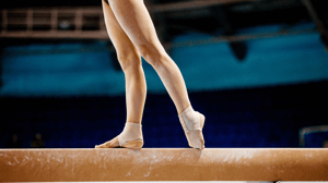 A gymnast stands on a balance beam.