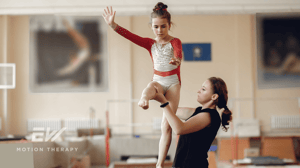 A young gymnast trains on the balance beam with her coach.