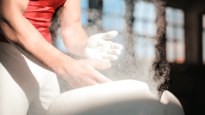 A gymnast chalks his hands.