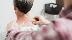 A man massages another man's shoulders. 