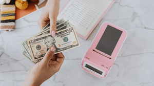 Two hands holding money across a table.