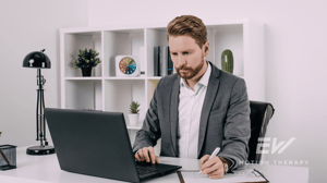 A man sits at his desk in his office.