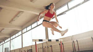 A woman leaps over a hurdle.