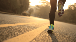 From the knee down, feet running on a paved road.