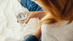A woman looks down at a glass of water.