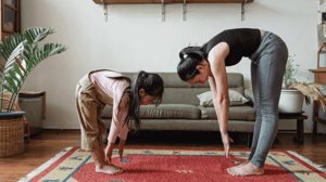 A woman and child bend over and touch their toes.