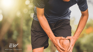A male runner grips his knee in pain.
