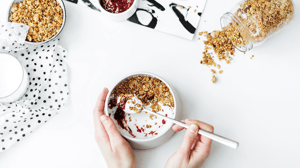 From above, a bowl of yogurt with granola and fruit.