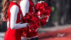 Two cheerleaders in red and white uniforms hold up red pom-poms.