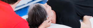 A woman lies on a table getting a neck massage.