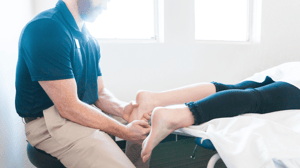 A man massages a woman's foot. 