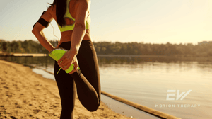 A woman stretches her leg during a run.