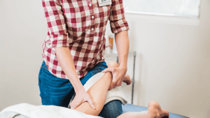 A physical therapist massages a patient's leg.