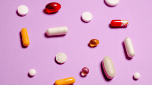 Flatlay of different pills on a purple background