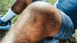 A man sits on the ground with bent knees.