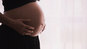 A woman holds her pregnant stomach on a white background