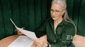 An older woman reads through paperwork.