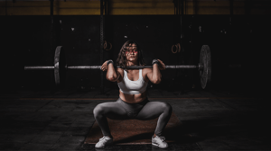 A woman sweats while lifting a barbell.