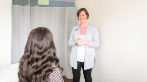 A woman standing talks to a woman sitting down.