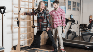 A man helps a woman balance on a CoreAlign machine.