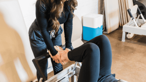 A Pilates instructor holds a participant's feet.