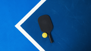 From above, a pickleball paddle and ball on the court