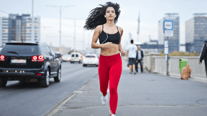A woman runs along a busy road.