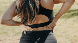 A woman holds her lower back.
