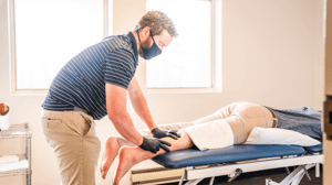 A man massages a person's leg as they lie on a table. 