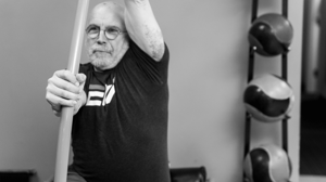 A man exercises with a mobility stick.