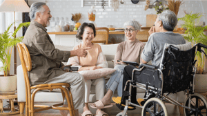A group of older people sit around a couch, talking and laughing.