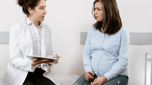 A woman sits with her female doctor.