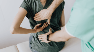 A woman receives manual therapy on her lower back.