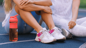 Two women sit on a pickleball court.