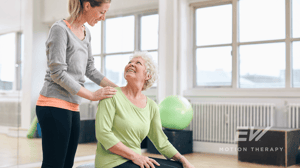 An older woman is guided through a Pilates class.