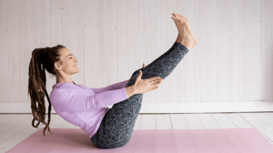 A woman exercises on a mat.
