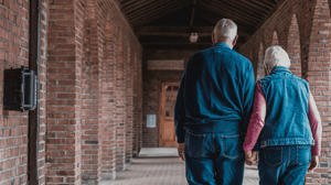 From behind, an older couple walks down a brick alleyway.