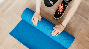 From above, a woman rolling up a yoga mat