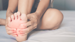 Hands holding a foot, sitting on a bed.