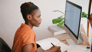 A woman sits at her desk looking at a computer.