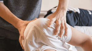 A physical therapist does manual therapy on a patient's shoulder.
