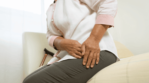 A woman holds her hip as she gets up from a couch.