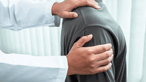 A doctor examines a man's shoulder.