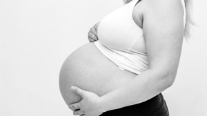 A black and white photo of a woman holding her pregnant belly.