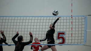 A volleyball player leaps up for a spike.