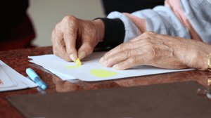 Wrinkled hands color a picture.