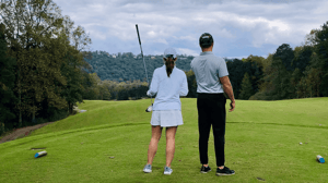 A man and woman look at a golf course.