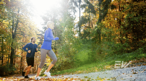 Two people running on a path through the woods.
